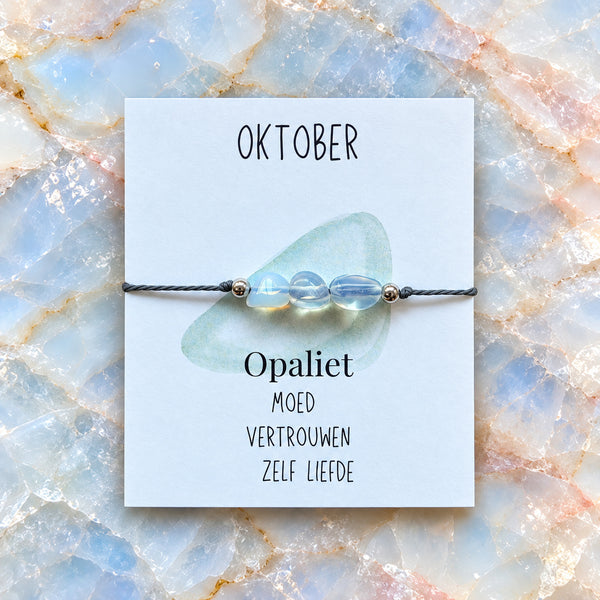 Maandarmband oktober op bijpassende edelsteenachtergrond